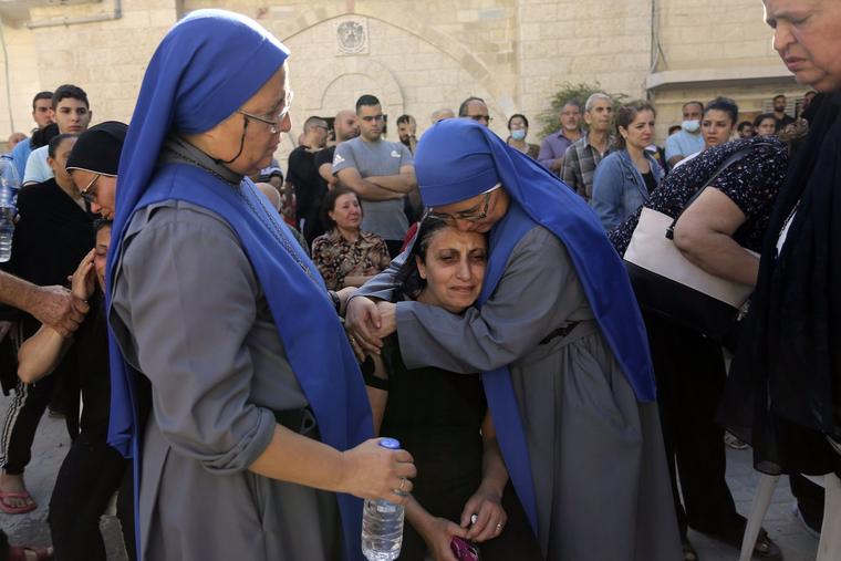 Nuns comfort a Palestinian woman as she mourns the death of a relative, killed in Israeli airstrikes that hit a church, during a funeral service in Gaza City, Friday, Oct. 20, 2023.