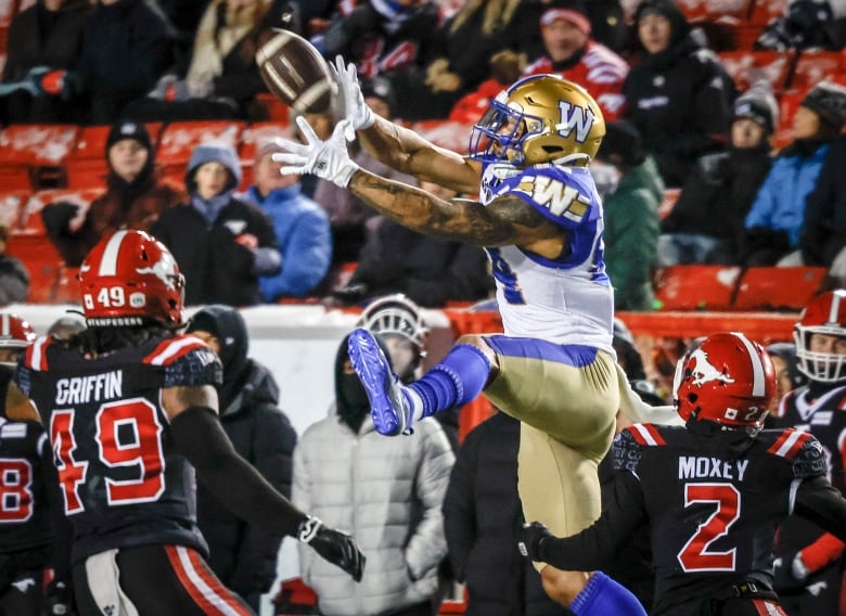 A football player jumps as he catches a football.