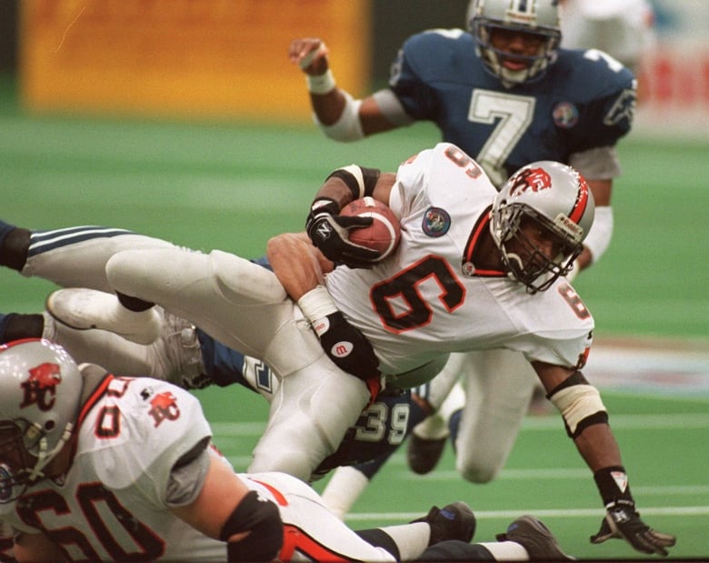 A male football player is seen being taken down by opposition players.