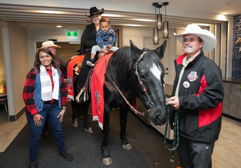 Diane Wensel, centre, rides Tuffy the horse with a young boy into the lobby of a hotel as the annual tradition kicks off Grey Cup festivities ahead of the 110th CFL Grey Cup between the Winnipeg Blue Bombers and Montreal Alouettes in Hamilton, Ont., on Thursday, November 16, 2023.