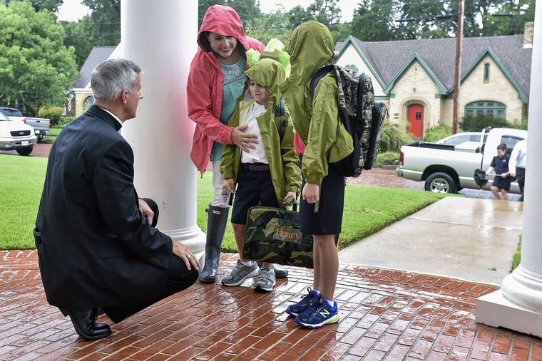 Bishop Joseph Strickland of the Diocese of Tyler, goes to one knee Wednesday, Aug. 17, 2016, to greet Betsy Jenkins and her sons, kindergartener Henry, center, and second-grader Bowen as they arrive for the first day of school at St. Gregory Cathedral School in Tyler, Texas.
