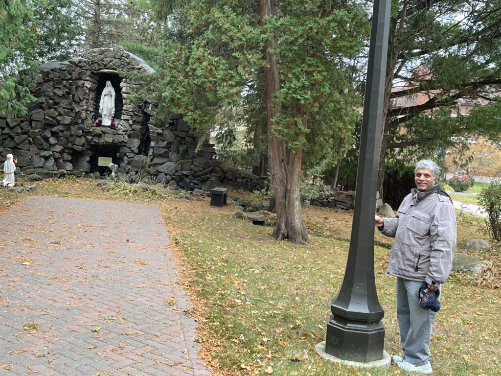 Patrick Norton stands beside the lamp post he was painting near the Marian grotto when he saw a woman in full Benedict habit who he believes was Sister Annella Zervas. Credit: Patti Armstrong