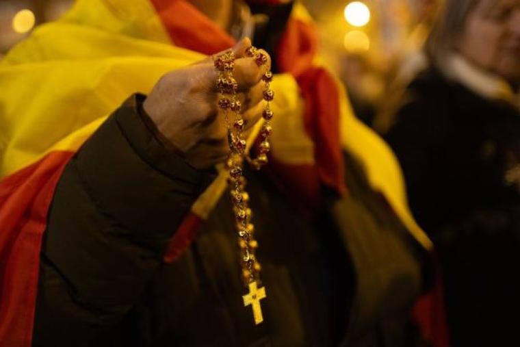 A man adorned in the flag of Spain prays the rosary for Spain on Dec. 8, 2023.