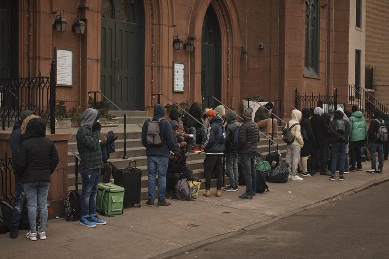Migrants wait in the cold as they look for a shelter outside a Migrant Assistance Center at St. Brigid Elementary School on Tuesday, Dec. 5, 2023, in New York.