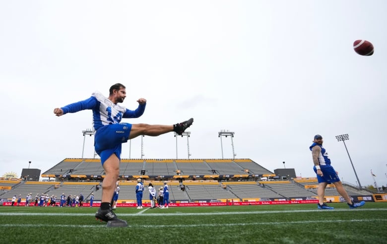 A football player in shorts punts a ball.