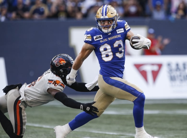 A football player escapes a tackle by an opposing player.