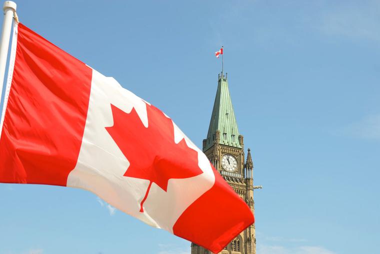 Canadian flag waving in front of the Parliament Building on Parliament Hill in Ottawa.