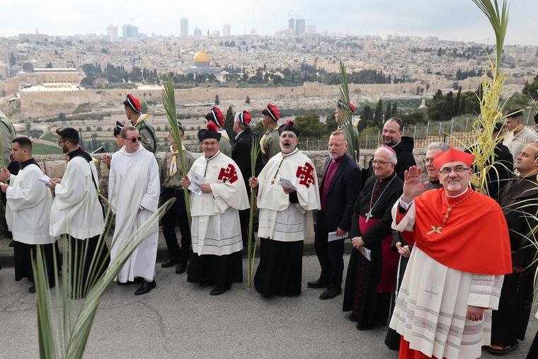 Pierbattista Pizzaballa, Latin patriarch of Jerusalem, waves from a road, overlooking the Dome of the Rock Mosque at the al-Aqsa Mosque complex, during the traditional Palm Sunday procession at the Mount of Olives in Jerusalem on March 24.