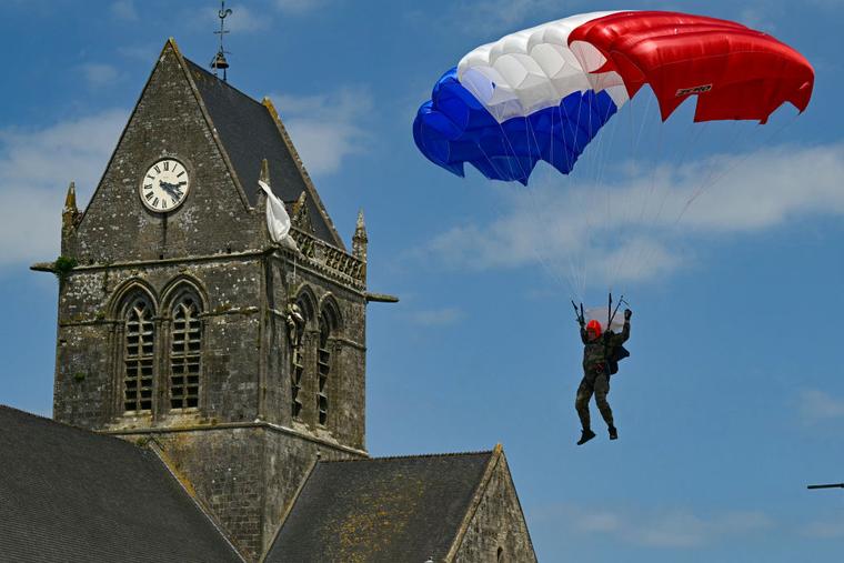 A French Marine Commando paratrooper guides his red, white and blue parachute canopy past the Church of Sainte-Mere-Eglise, where a mannequin effigy of World War II veteran U.S. Army 82nd Airborne paratrooper John Steele hangs from the steeple, in Sainte-Mere-Eglise, northwestern France, on June 5, as part of the D-Day commemorations marking the 80th anniversary of the World War II Allied landings in Normandy.