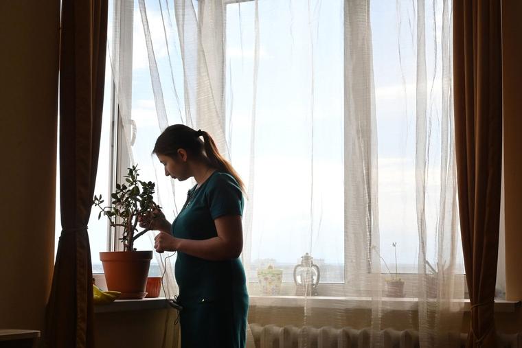 In this photograph taken June 4, 2020, Olga Korsunova, a 27-year-old going through her fourth surrogate pregnancy, tends to plants in her rental flat in Kiev, Ukraine.