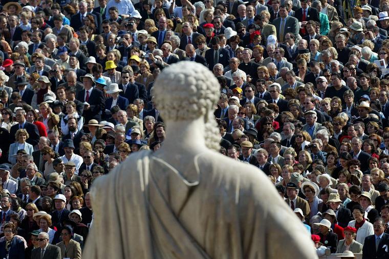 Pilgrims stand in front of a statue of St. Peter in St. Peter’s Square as Pope St. John Paul II offers the canonization Mass for Opus Dei founder St. Josemaria Escriva de Balaguer, Oct. 6, 2002. An estimated 250,000 pilgrims from around the world attended the ceremony.