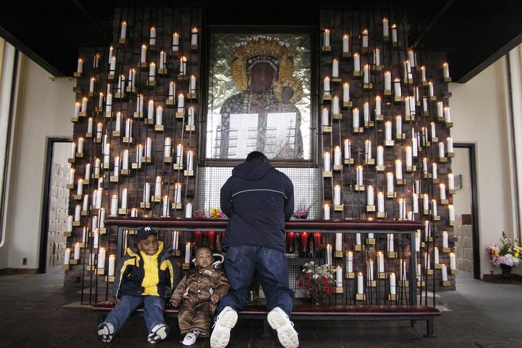 L-R: Rodney Chery, Sebastien Chery, 9-months-old, and their father, Rony Chery, of Haiti, pray for Pope John Paul II in the Candlelight Chapel at the National Shrine of Our Lady of Czestochowa on April 2, 2005, the day of the papal death, in Doylestown, Pennsylvania.