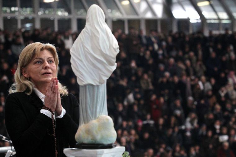Mirjiana Dragicevic, one of the alleged visionaries, prays in front of a statue of Our Lady of Medjugorje, during a religious event in Naples, Italy.