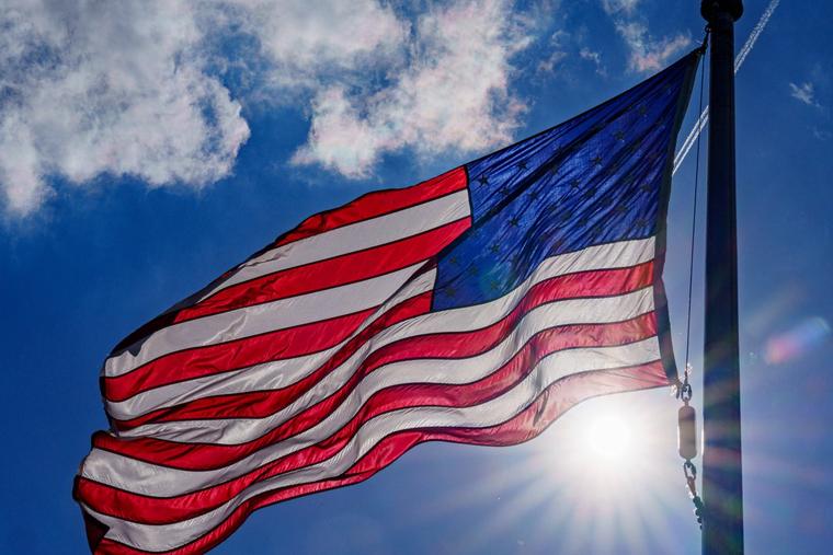 The sun flares below the U.S. flag on the National Mall on April 18, 2024, in Washington.