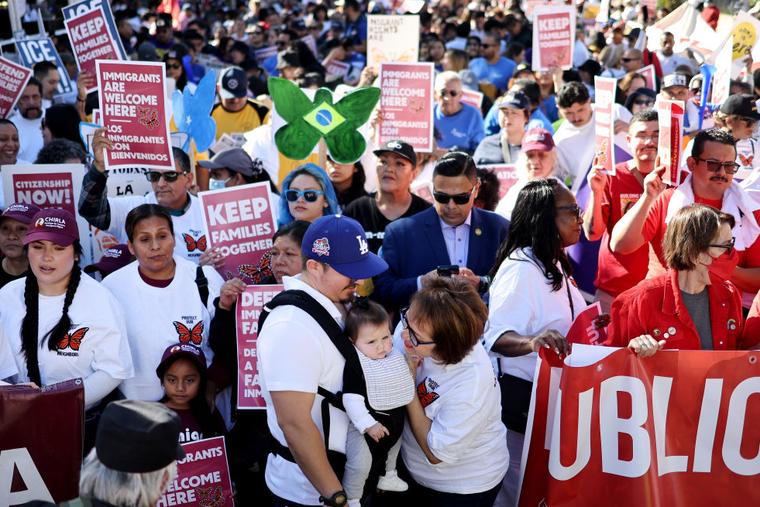 Immigrant rights supporters hold signs before they march to an ICE detention center on International Migrants Day on December 18, 2024 in Los Angeles, Calif. The march was led by CHIRLA with marchers calling for President Biden to protect immigrant families ahead of President-elect Trump’s planned wave of migrant deportations.