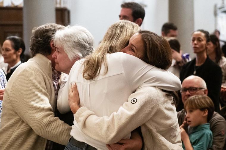 Victims of the Palisades Fire hug during a special Mass for the burned-down Corpus Christi Church at St. Monica in Santa Monica on Jan. 12, 2025.