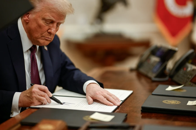 President Donald Trump signs executive orders in the Oval Office of the White House.
