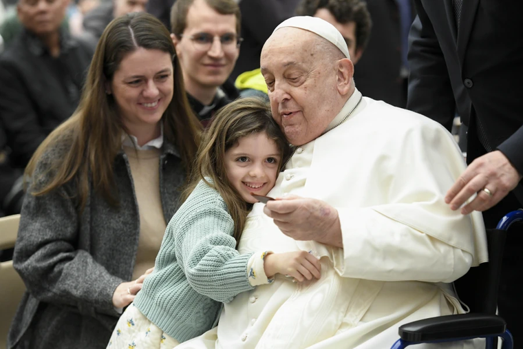 Pope Francis is hugged by a young visitor at his general audience at the Vatican, Wednesday, Feb. 12, 2025.