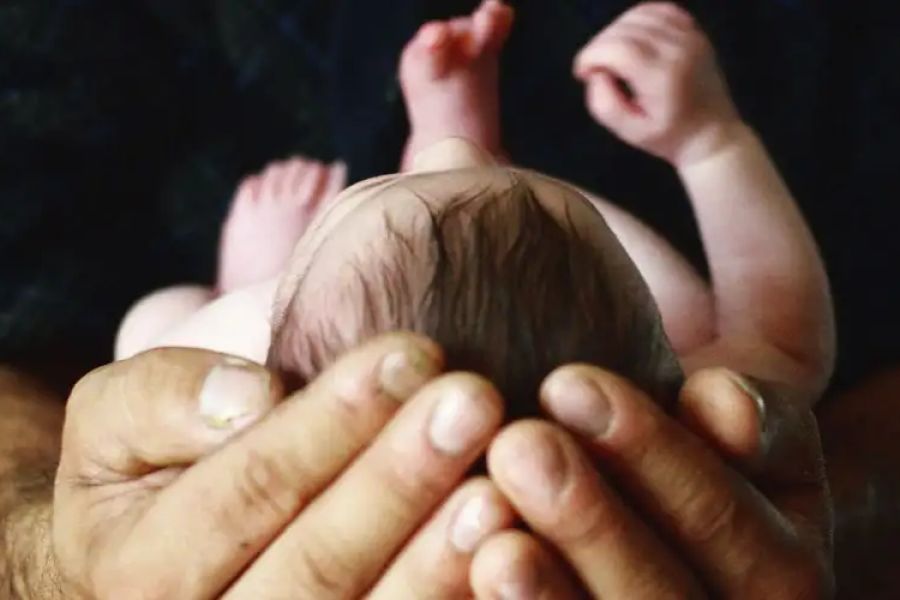 A father holds a newborn in his hands.