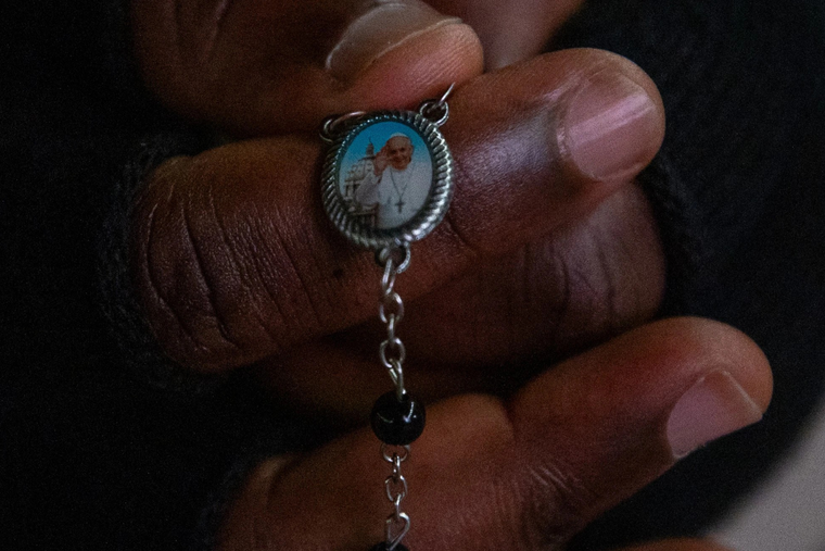 A person holds a rosary with a medal bearing Pope Francis’ image during the nightly prayer vigil in St. Peter’s Square on Feb. 28, 2025.