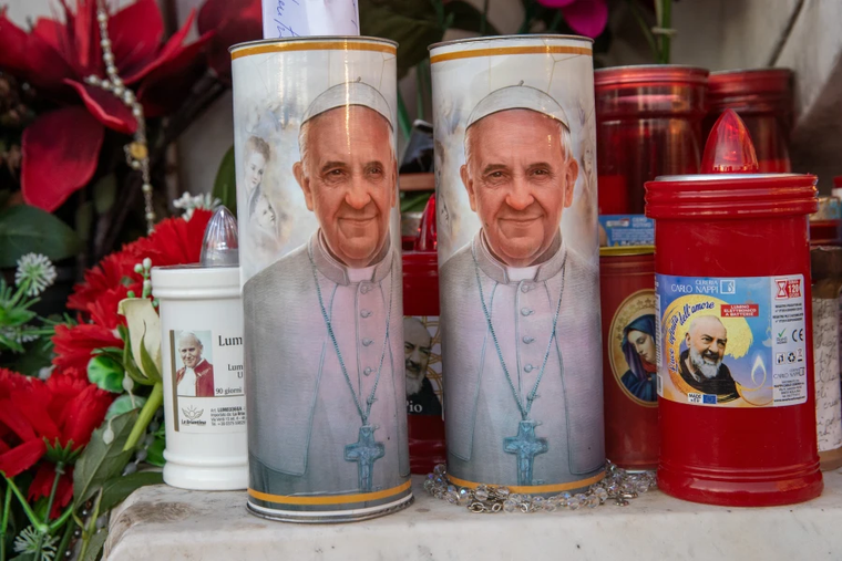 Candles with Pope Francis’ image on them stand outside Gemelli Hospital in Rome on Feb. 21, 2025.
