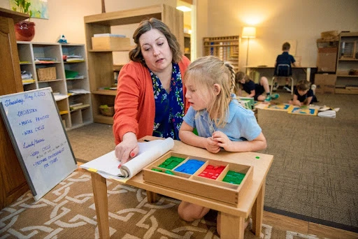 Lower Elementary guide Cate Zweber helps a student with a math game in spring 2023 at the Christ the King Catholic Montessori Grade School. The grade school was a success story for Montessori education and the impetus for the UMary Montessori master’s degree. Credit: Mike McCleary/University of Mary