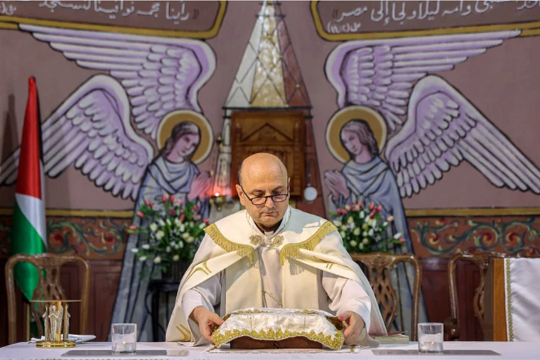 Father Gabriel Romanelli, of Holy Family Church, who was wounded in a recent strike on the church, stands before the altar during a Sunday morning Mass held by the Latin patriarch of Jerusalem at the church in Gaza City on July 20, 2025.