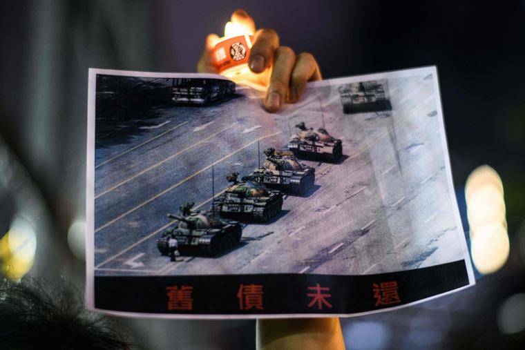 A man holds a poster of the famous 'Tank Man' standing in front of Chinese military tanks at Tiananmen Square in Beijing on June 5, 1989, during a candlelit remembrance in Victoria Park in Hong Kong on June 4, 2020.