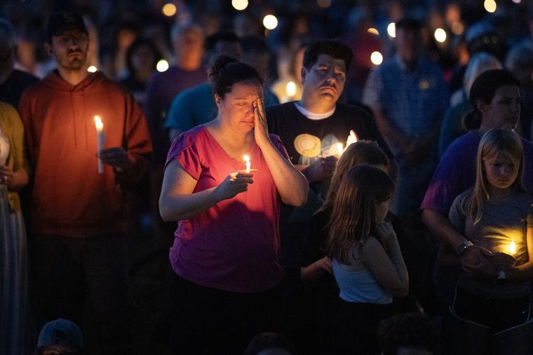 People attend a vigil at Lynnhurst Park to mourn the dead and pray for the wounded after a gunman opened fire on students at Annunciation Catholic School on Wednesday in Minneapolis.