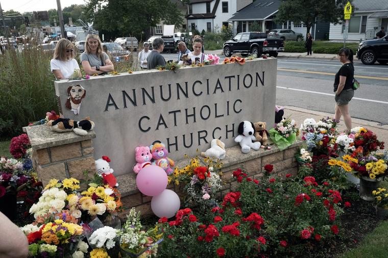 People leave flowers and other mementoes in front of Annunciation Catholic Church on Thursday; the memorial to the victims of Wednesday’s shooting in Minneapolis is rapidly growing.