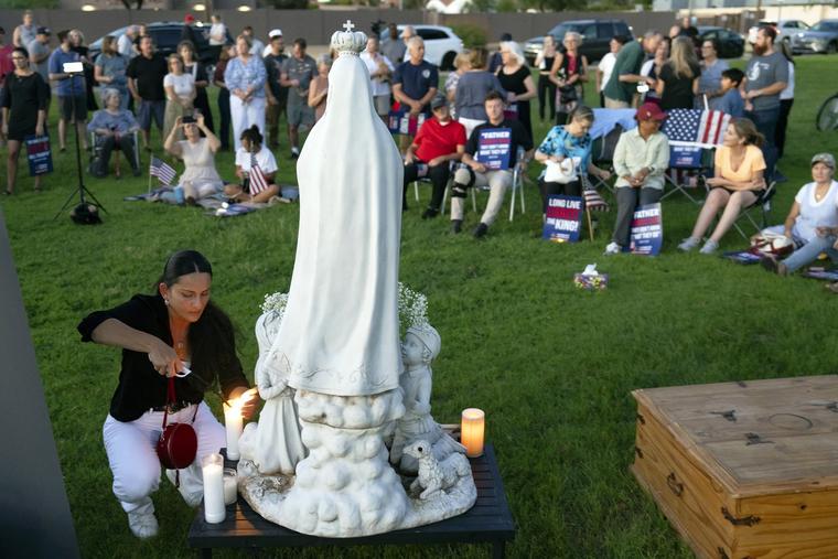 A woman lights a candle before a statue of Our Lady of Fatima on Wednesday during a prayer vigil for Turning Point USA founder Charlie Kirk at Desert Horizon Park in Scottsdale, Arizona.