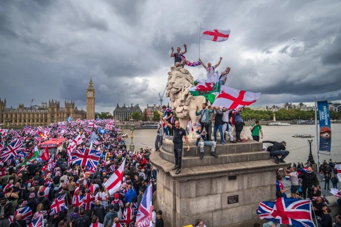 Protesters wave the Union Jack and St. George’s Cross flags during the “Unite the Kingdom” rally on Westminster Bridge by the Houses of Parliament on Sept. 13, 2025, in London.