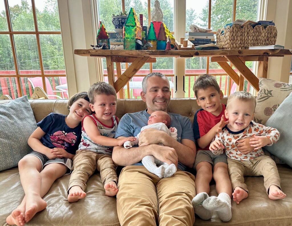 Ryan Anderson sits with his children at home holding the newest arrival to the family.