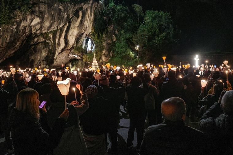 Pilgrims hold candles during Mass Nov. 1, 2024, at Lourdes.