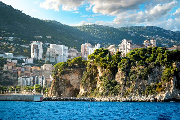 Monaco Cathedral (r) rises above the rocky coastline overlooking Fontvieille Harbor, with high-rise buildings in the background, in Monte Carlo, Monaco.