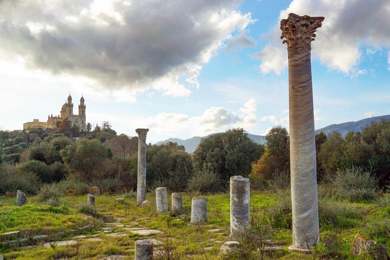 The Roman ruins of the ancient city of Hippo stand in the foreground, with the Basilica of St. Augustine rising in the background in Annaba, Algeria.
