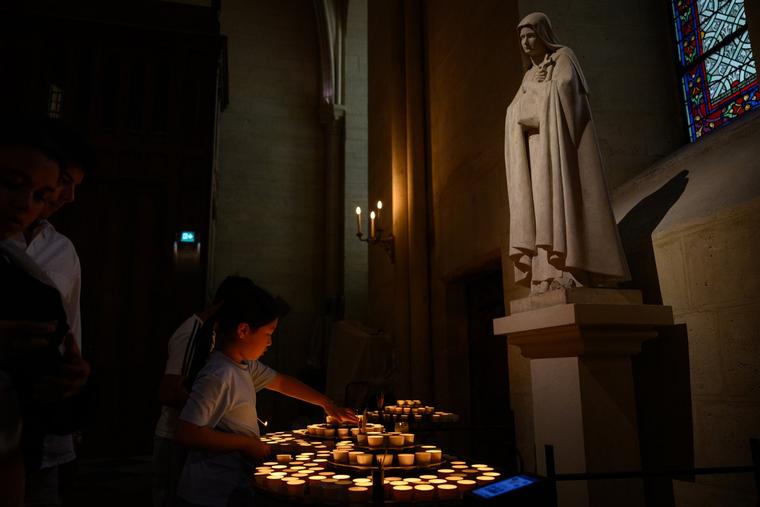 A boy lights votive candles in Notre Dame Cathedral on Aug. 26, 2025, in Paris.