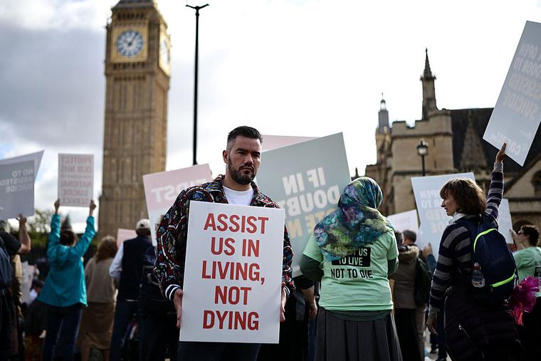 A campaigner against a change in the law on assisted dying holds a placard outside The Palace of Westminster, home to the Houses of Parliament in central London, on September 11, 2026.